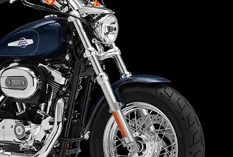 Sportster XL 1200 Custom / Beeindruckende Frontpartie:    Die Frontpartie der Sportster 1200 Custom fllt dem Betrachter unmittelbar ins Auge. Ihre krftigen Gabelbrcken sind ebenso unverkennbar wie der breite Vorderreifen auf dem verchromten fnfspeichigen 16-Zoll-Rad. Schauen Sie genau hin. Was Sie hier sehen, ist der unverflschte Charakter einer echten Sportster, nur einen Touch wuchtiger und mit etwas mehr Custom-Style.
