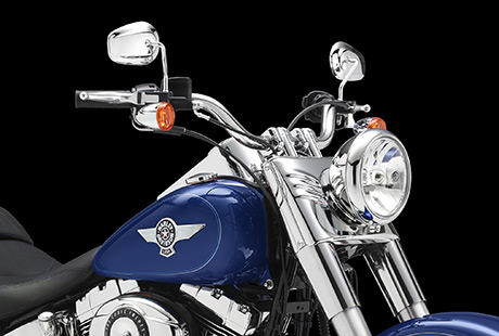 Softail Fat Boy / Fat-Features mit 200er-Reifen:    Die silberfarbenen 17-Zoll-Scheibenrder aus Leichtmetallguss im Bullet Hole Design machen mchtig Eindruck  nicht zuletzt dank der ppigen Bereifung: Vorn rotiert ein feister 140er, am Heck ein Gummi im 200er Format. Der extrabreite Edelstahl-Lenker ruht auf verchromten Risern im Bare Knuckle Design. Selbst die Tankembleme glnzen mit einer Extraportion gleienden Chroms. Ein solches Bike zieht berall die Blicke auf sich.
