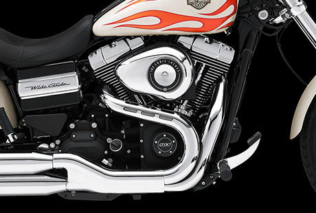 Dyna Wide Glide / Motor im Harley-Davidson Styling pur:    Genieen Sie den unverwechselbaren Look des Twin Cam 103 Motors, der an seiner Herkunft keine Zweifel aufkommen lsst. Er ist voll und ganz im echten Harley-Davidson Stil gestaltet. Die schwarzen, pulverbeschichteten Zylinderkpfe und Zylinder bilden einen prgnanten Kontrast zu den polierten Khlrippenkanten und verchromten Ventildeckeln. Ein aus Metall gefertigtes Juwel: pur und vor Kraft strotzend. Von der klassischen Linie seiner Khlrippen bis hin zu den klaren Konturen seiner Gehuse und Deckel ist der Twin Cam 103 ein rckhaltloses Bekenntnis zu allem, was die Zufriedenheit des Fahrers ausmacht.
