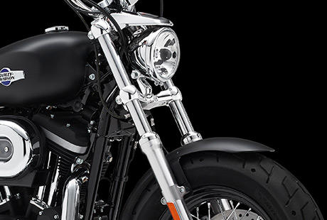 Sportster XL 1200 Custom Limited B / Breite Frontpartie:    Die Frontpartie der 1200 Custom Limited Edition B fllt dem Betrachter unmittelbar ins Auge. Ihre krftigen Gabelbrcken sind ebenso unverkennbar wie der breite Vorderreifen auf dem schwarzen 16-Zoll-Drahtspeichenrad. Schauen Sie genau hin. Was Sie hier sehen, ist der unverflschte Charakter einer echten Sportster, nur einen Touch wuchtiger und mit etwas mehr Custom-Style.
