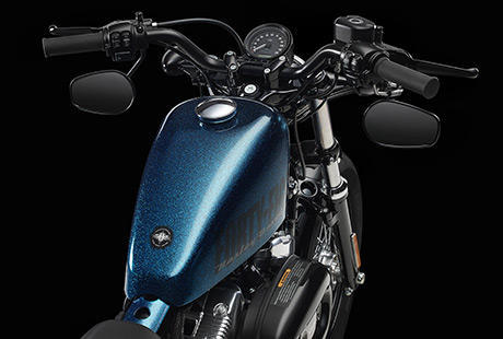 Sportster Forty-Eight / Cooler Lenker, klassischer Tacho und unter dem Lenker montierte Spiegel:    Der niedrige schwarze Drag Bar Lenker mit Tachometer und nach unten ausgerichteten Spiegeln betont den puristischen, minimalistischen Look der Forty-Eight. Der Drag Bar Lenker wurde von den Hot-Rod-Pionieren vergangener Zeiten inspiriert. Er ist Ausdruck des Old-School-Stylings und gestattet dem Fahrer eine extracoole Sitzposition.
